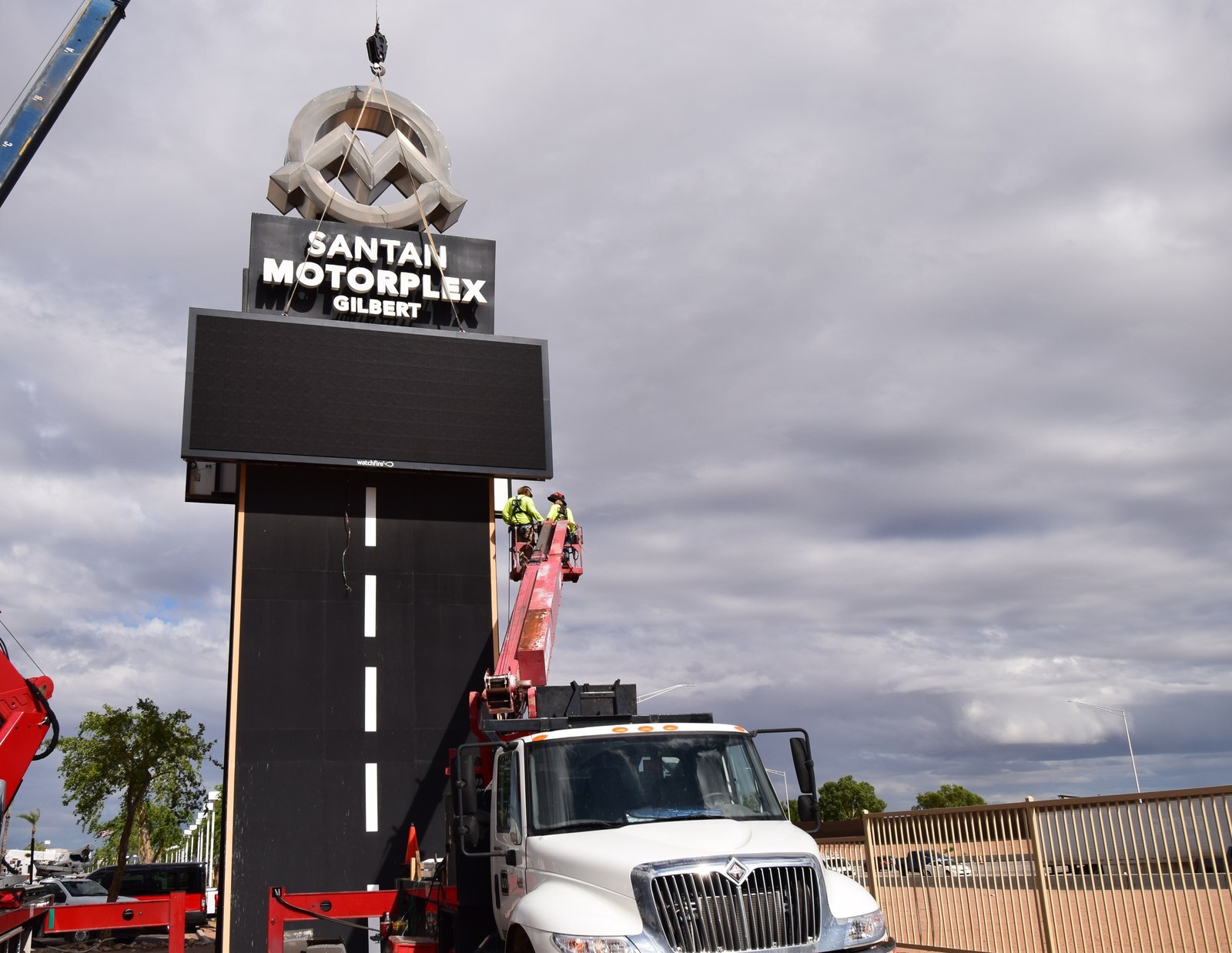 Two installers in a bucket truck work on the new LED display cabinet on the San Tan Motorplex tower