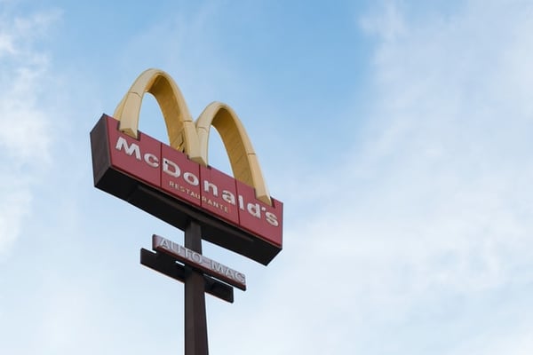 McDonald's sign during daylight in front of a blue sky with soft white clouds.