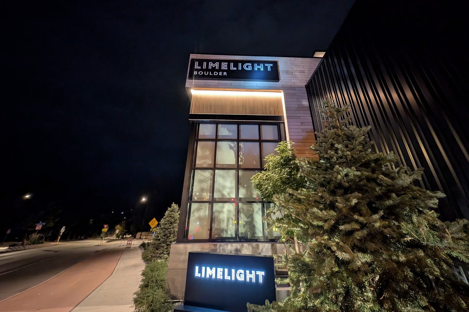 Limelight Boulder illuminated tower and ground signs at night, Boulder, CO